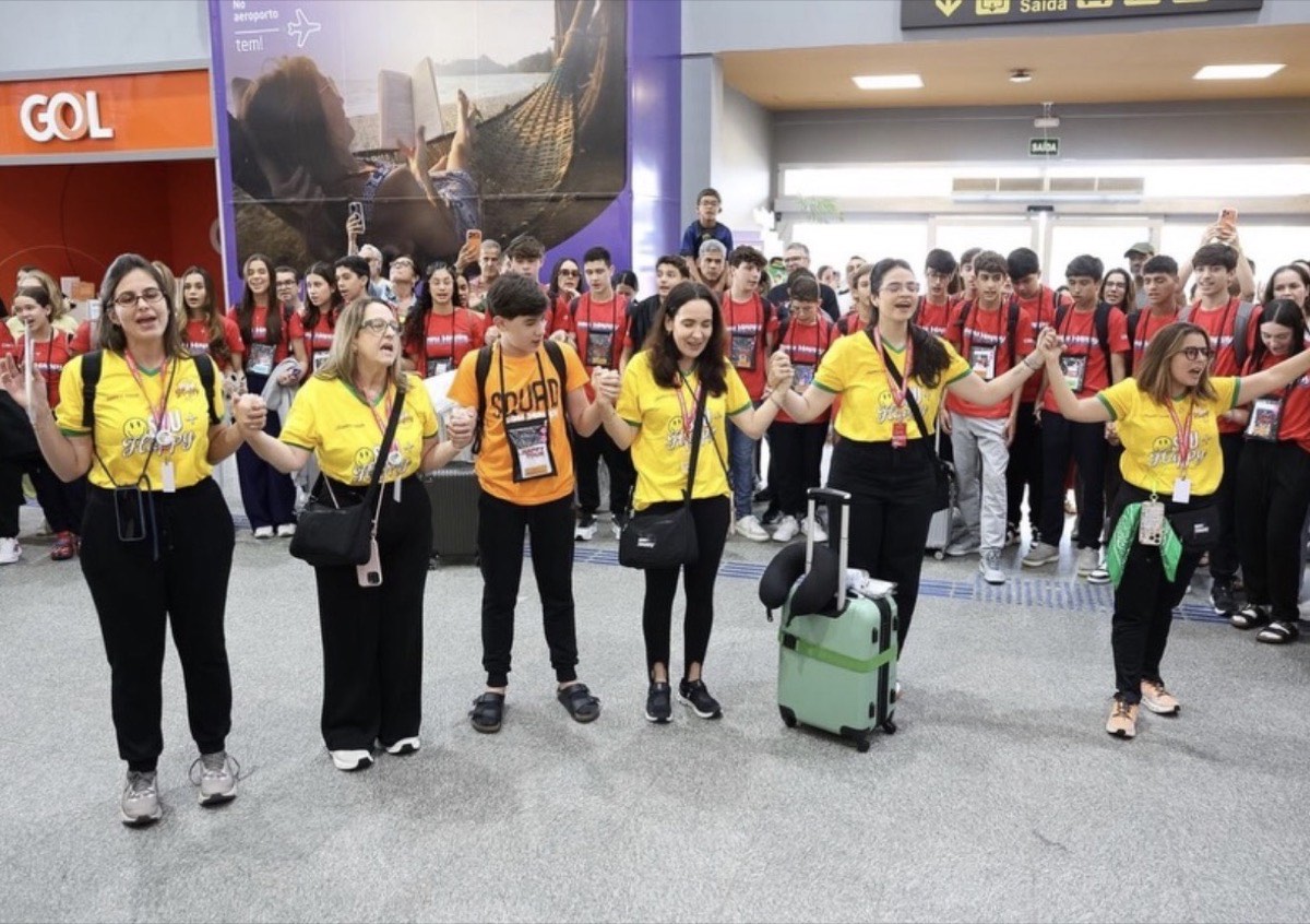 Monitoras da Papagaios de mãos dadas com os adolescentes no aeroporto, no dia do embarque